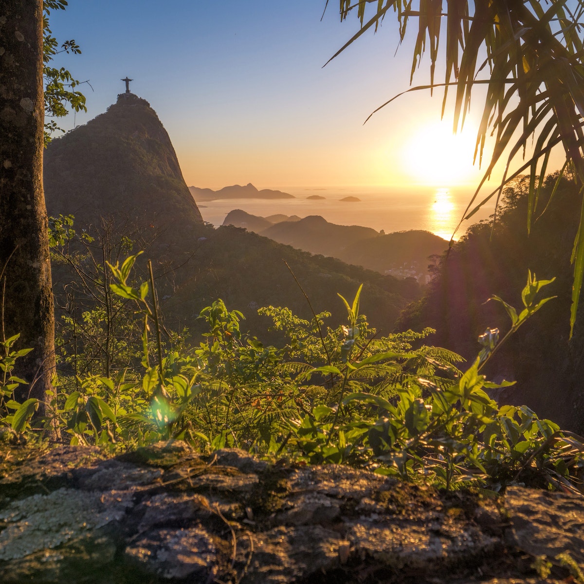 The sunset with Christ The Redeemer on the Corcovado Hill viewed from Paineiras Road at Tijuca Forest with the Atlantic Ocean in the distance.