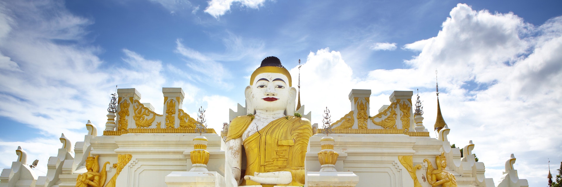 Novice monks cycling past 26-foot high sitting Buddha at Yan Aung Nan Aung Hsu Taung Pyi Pagoda near Inle Lake.