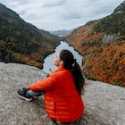 Hiking in the Adirondack Mountain Indian Head Trail in the fall
A woman sits on a rock overlooking a river and the Adirondacks mountains in the fall