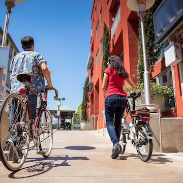 A man and woman with their bicycles near a light rail station in Pasadena, California.