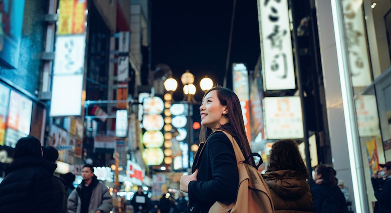 Smiling young Asian female traveller exploring and strolling along the busy and colourful neon signboard downtown city street at night in Osaka, Japan
1202888936