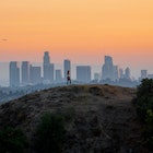 Woman standing on hill with Downtown Los Angeles cityscape in the background.
1444914619