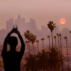 A woman takes a photo of the sunset in Los Angeles