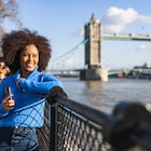 A Black woman looking at the River Thames in front of Tower Bridge