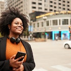 Immersed in the urban rhythm, a woman in a suit and headphones stands in downtown Chicago, awaiting her carpool with poised anticipation.
1498638733
A woman smiling on the side of the street in Chicago