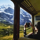 Woman taking photo with a smartphone of Jungfrau while riding in train