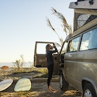 Features - Side view of male surfer having drink outside mini van on San Onofre State Beach