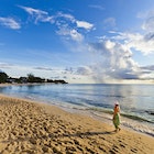 Woman walking on the beach of Paynes Bay at sunset. Surrounded by a beautiful stretch of sand, this is one of the most popular beach on the west coast of Barbados. Canon EOS 5D Mark II