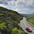 E-Type Jaguar driving on country road between Kenmare and Killarney.