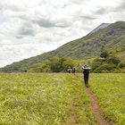 San Jacinto, Nicaragua - June 18, 2015: Group of hikers walks through the field and is about to ascend the slopes of the very active Telica volcano in San Jacinto, Leon, Nicaragua. Central America