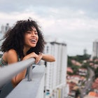 Panama, Panama City, portrait of happy young woman on balcony - stock photo