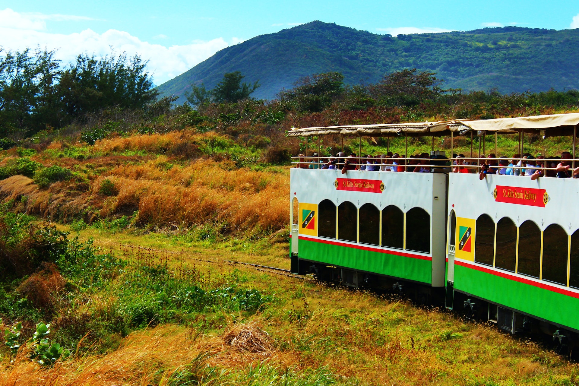 People ride along in double-decker train carriages with open-air top decks so they can watch the scenery go by