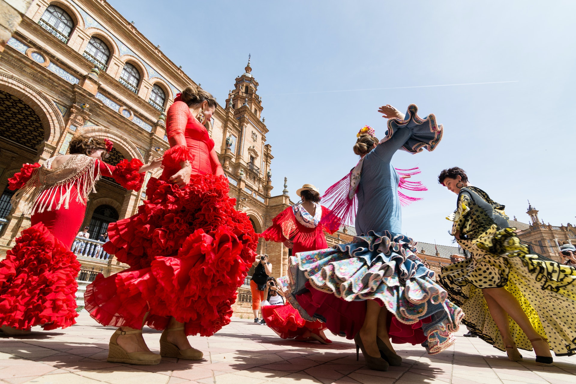 Flamenco dancers in colorful traditional dresses dance in a square