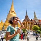 Young woman traveler with backpack traveling into beautiful pagoda in Wat Pra Kaew.